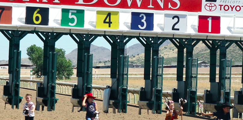 Kids on stick horses in front of a starting gate.